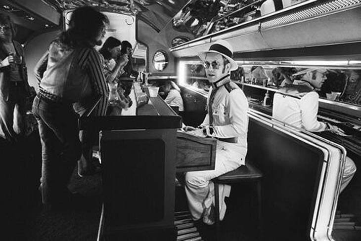 Elton John at the piano bar aboard his private plane - 1976