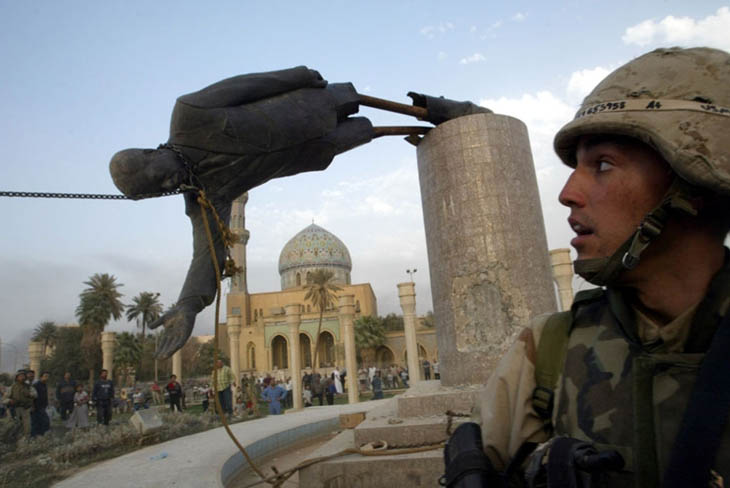 A month and a half after the invasion began, U.S. Marine Kirk Dalrymple watches as a statue of Iraq's President Saddam Hussein falls in central Baghdad. [2003]