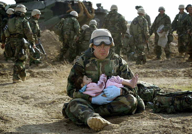 U.S. Navy Hospital Corpsman HM1 Richard Barnett, assigned to the 1st Marine Division, holds a child after she was separated from her family during a firefight [2003]