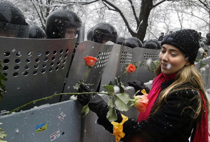 A Ukrainian woman places carnations into shields of anti-riot policemen