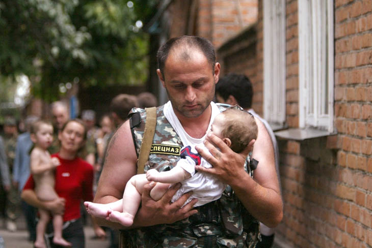 A Russian police officer carries a released baby from the school