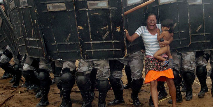 An indigenous woman holds her child while trying to resist the advance of Amazonas state policemen