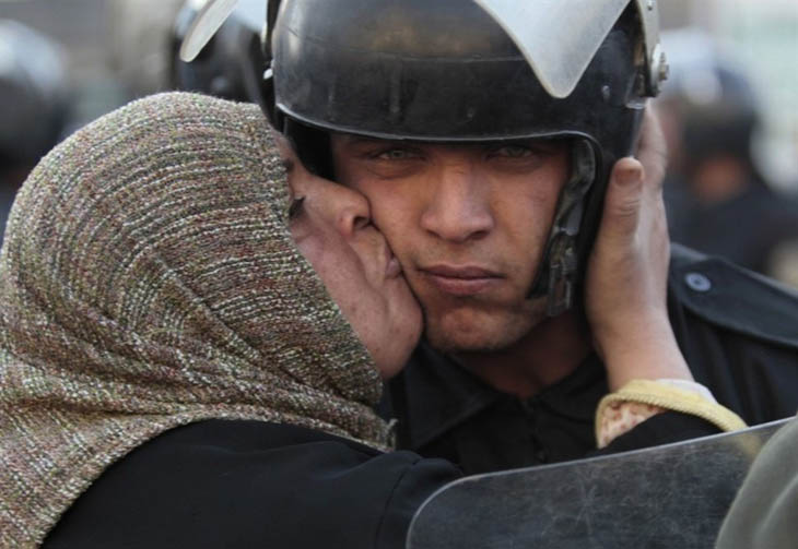 An Egyptian woman kisses a policeman, who had refused to fire on protestors