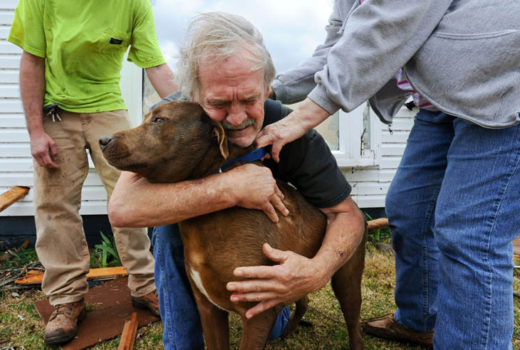 Greg Cook hugs his dog Coco after finding her inside his destroyed home in Alabama following the Tornado. [2012]