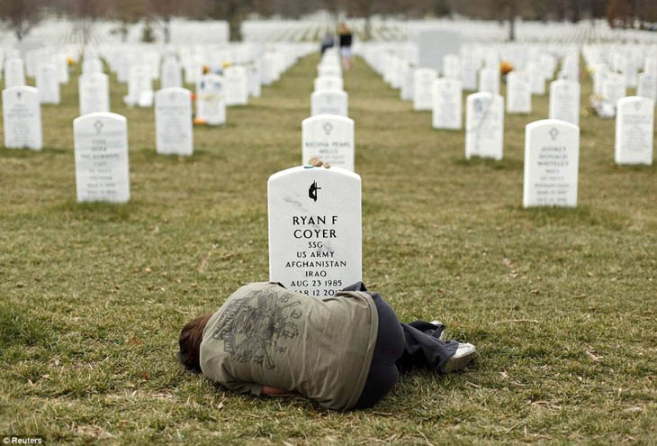 Lesleigh Coyer, 25, of Saginaw, Michigan, lies down in front of the grave of her brother, Ryan