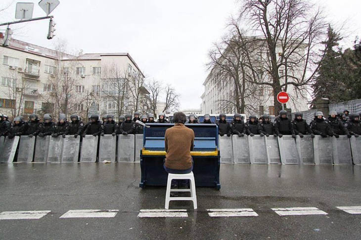 21st century photos - Markiyan Matsekh plays piano for police during the Ukranian revoloution. [2014]