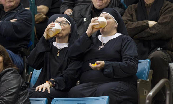 Two women wearing nun outfits drink beer while watching the 2014 Tim Hortons Brier curling championships in Kamloops, British Columbia.