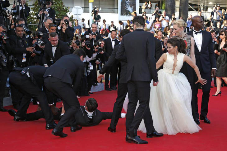 A man is arrested by security as he tries to slip under the dress of actress America Ferrera in Cannes.