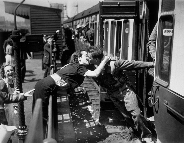 Wartime photos: A Woman Leans Over The Railing To Kiss A British Soldier Returning From World War II, London, 1940